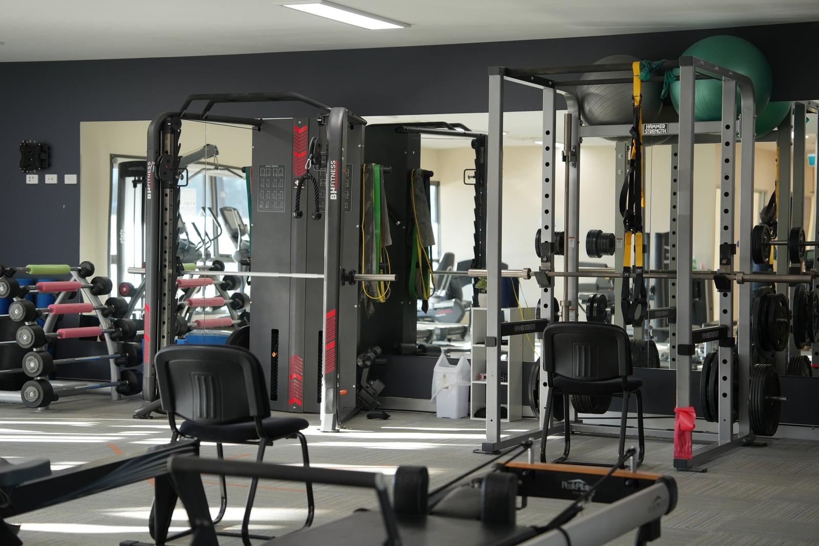 The Goulburn Health Therapy clinical gym — Concept2 rower, Pilates reformer, dumbbell rack, and cable machines across an open carpeted floor