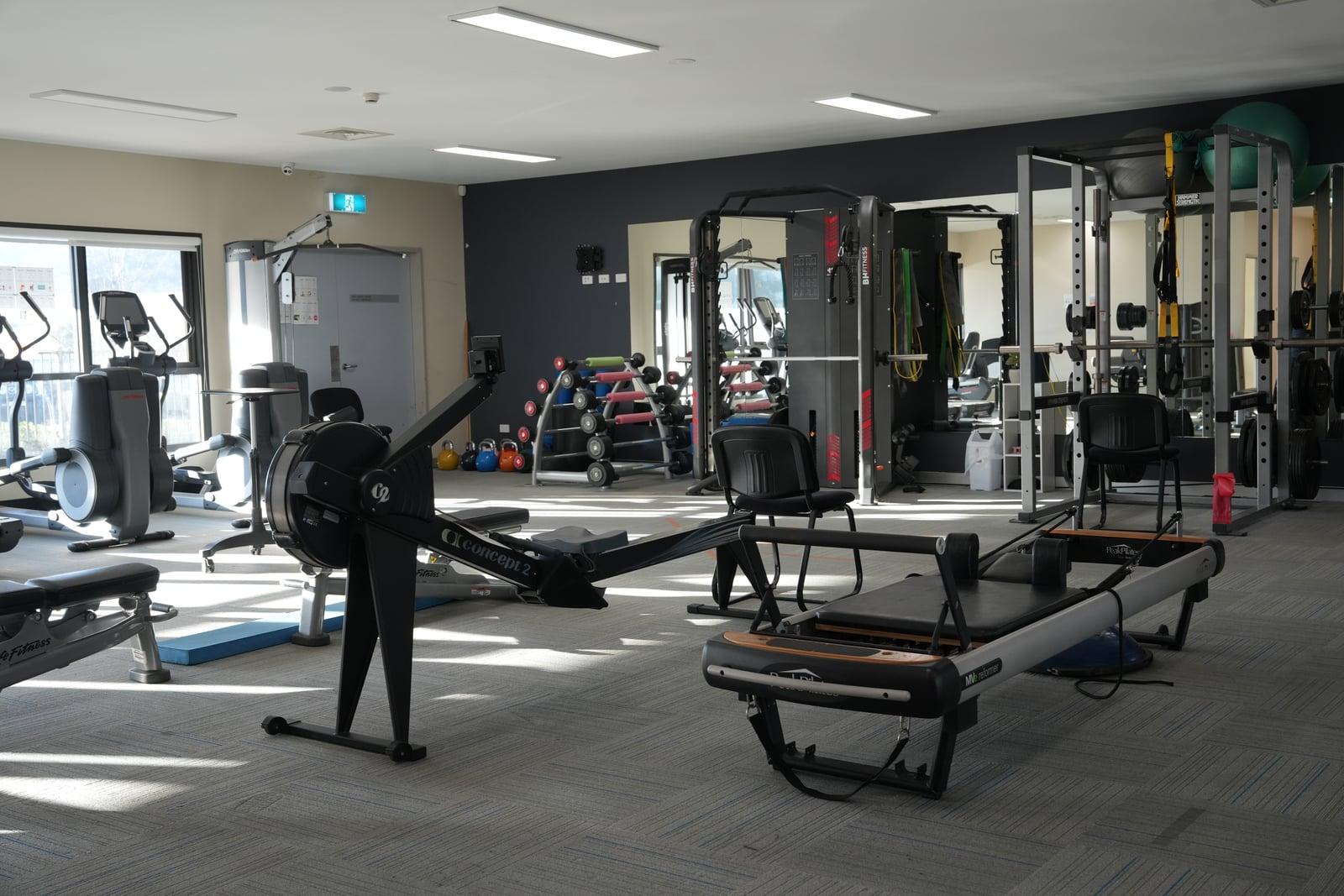 The strength corner at the Goulburn clinic — Hammer Strength power rack with weighted plates beside a dual-stack cable machine