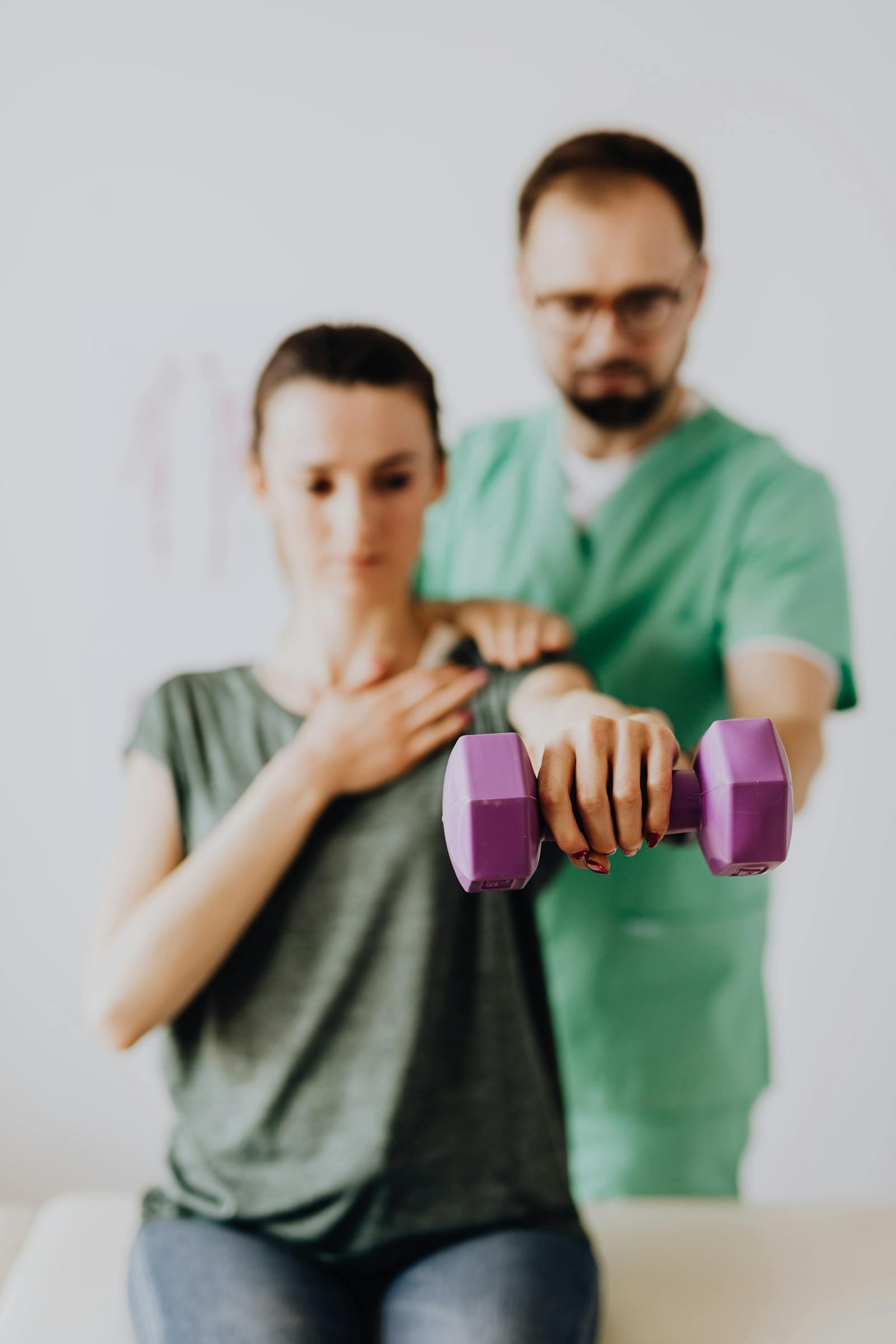 An occupational therapist guiding an adult patient through a dumbbell-resistance exercise