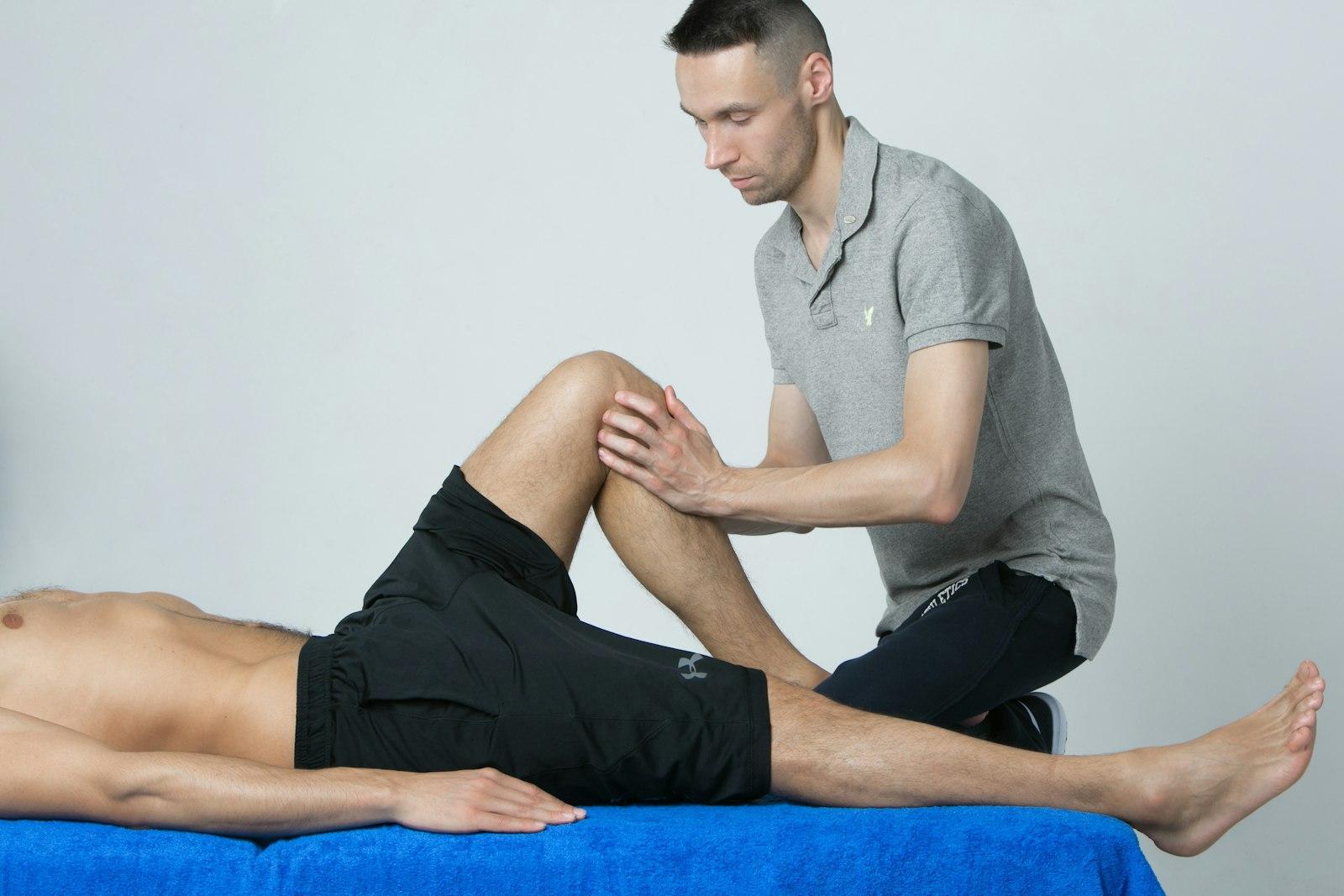 Physiotherapist performing manual knee joint mobilisation on a treatment table