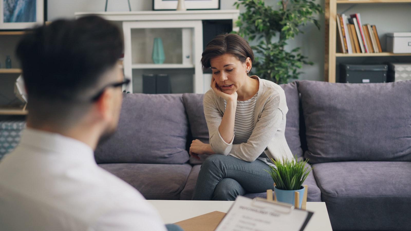 An adult client in conversation with a therapist on a sofa