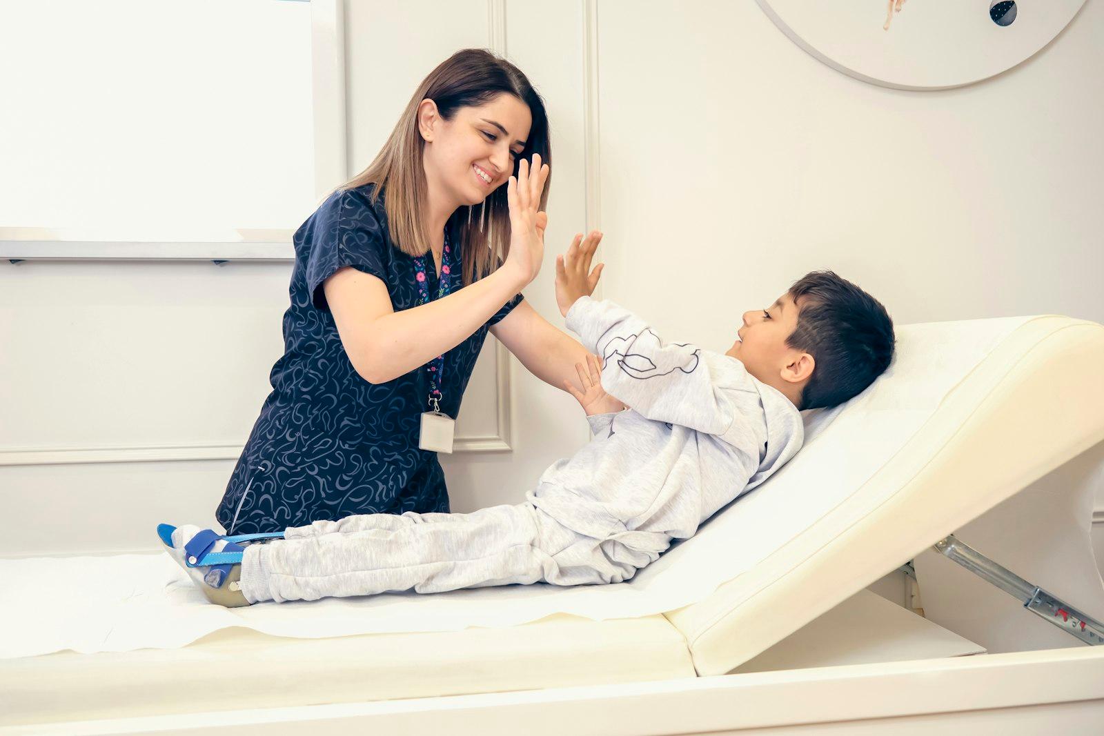 A paediatric clinician sharing a high-five with a young boy during a therapy session