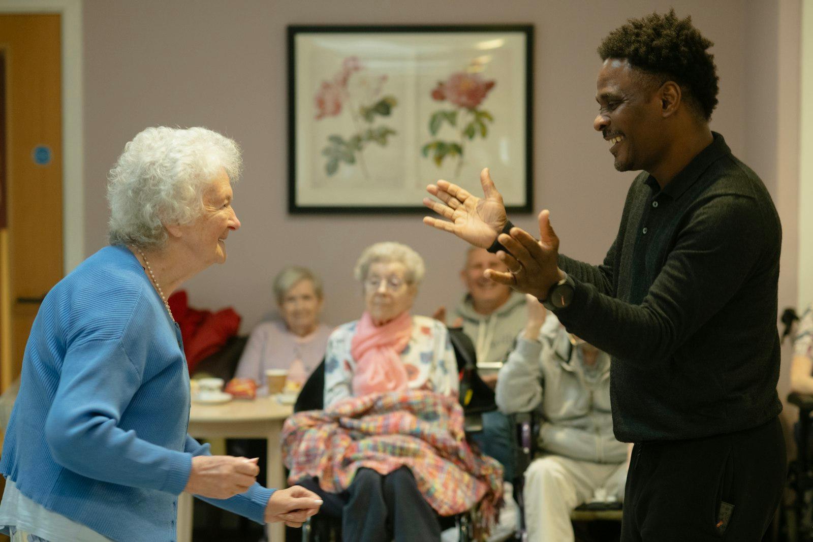 A clinician communicating with an older woman in an aged-care lounge
