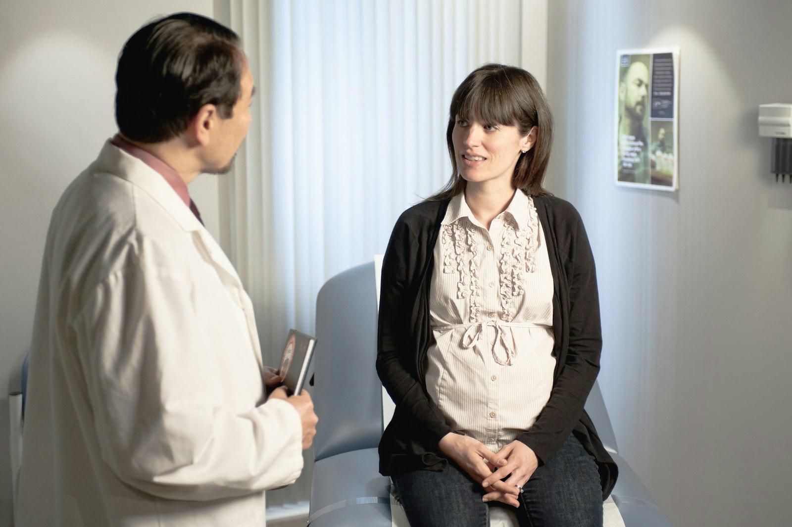 A clinician talking with a seated pregnant patient in a private consultation room