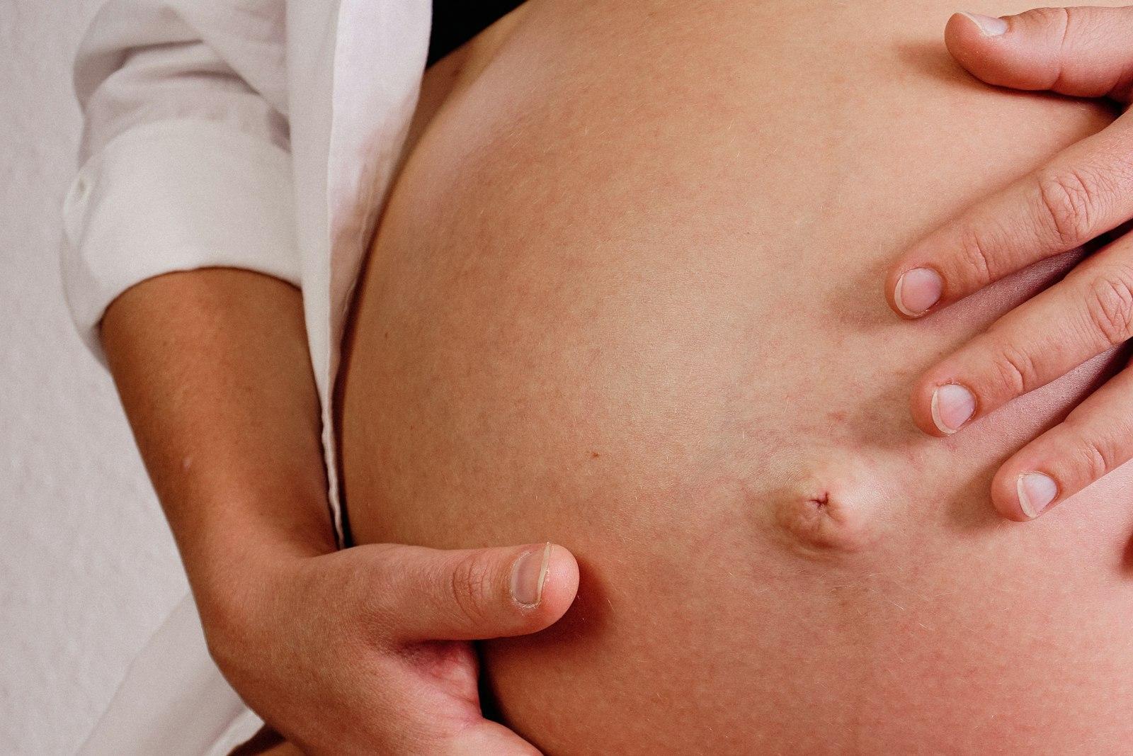 A clinician's hands resting on a pregnant belly during an antenatal assessment
